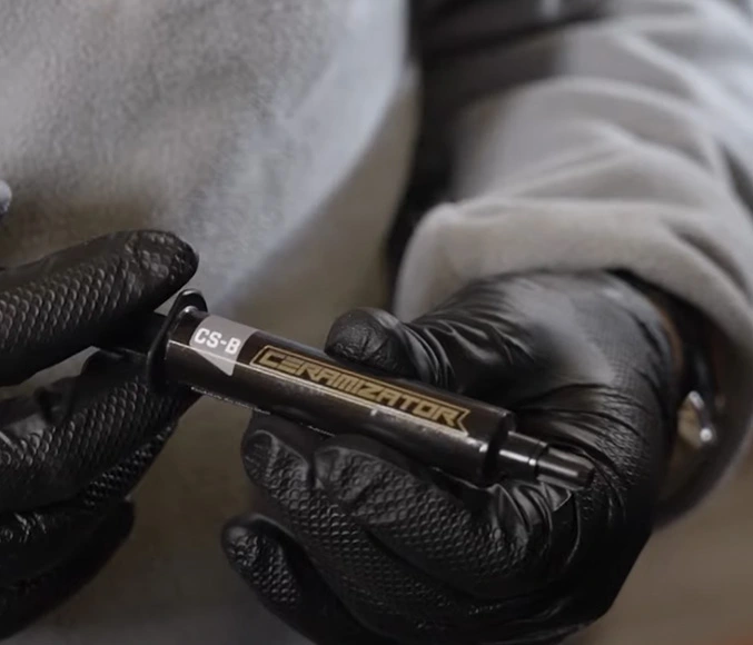A Ceramizator CS-B applicator held in gloved hands